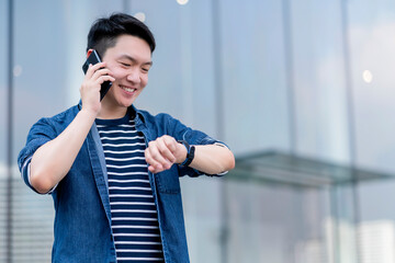 young smart attractive asian confident male wearing casul cloth hand hold smartphone connect communication near modern building smart technology ideas concept