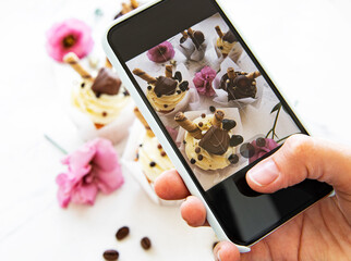 Girl makes a photo of cupcakes on a smartphone