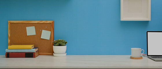 Worktable with books, laptop, notice board, decoration and copy space