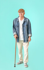 Canvas Print - Senior man with walking stick on color background