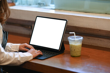 Young woman searching information in websites on tablet computer in coffee shop.