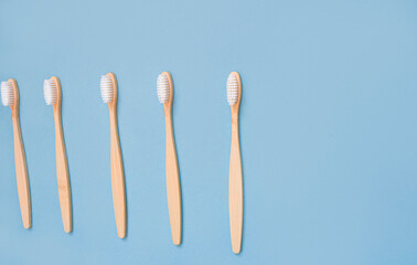 A family set of five eco friendly wooden bamboo toothbrushes on a light blue background. Oral cavity care. The concept of environmentally friendly recycling of toothbrushes. Angled copy space for text