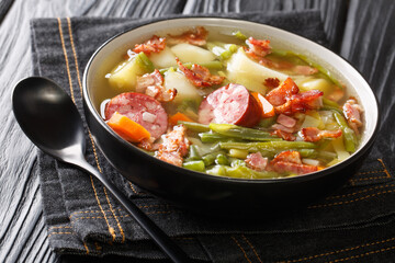 Bouneschlupp Green Bean And Potato Soup with bacon, onions sausages close-up on a plate on the table. Horizontal