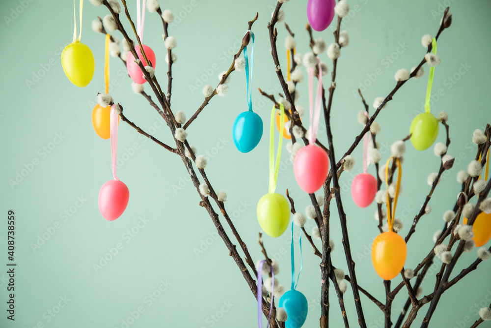 Bunte Ostereier an Osterstrauß aus Zweigen von Sal-Weide mit Weidenkätzchen Kätzchen vor Pastell Grün Hintergrund zu Ostern Stock Photo