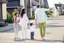 Back Side Photo Of Nice Optimistic Family Walk Hold Hands Near Home Wear Casual Cloth Outside