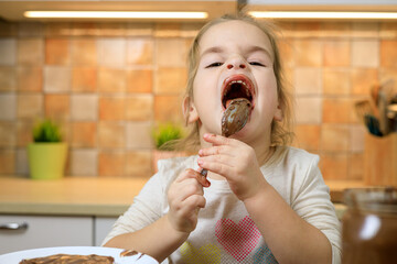 Little girl eating chocolate cream by spoon