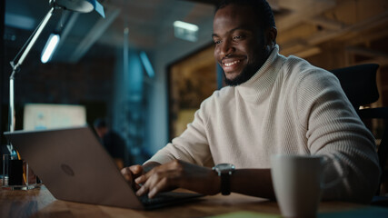 Aufkleber - Handsome Black African American Man Having an Online Conversation on a Laptop Computer in Creative Office Environment. Happy Male is Browsing Social Media and Replying to Friends in Messenger.