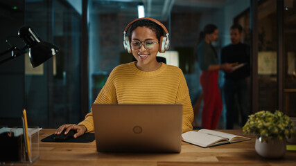 Aufkleber - Young Hispanic Project Manager in Headphones and Working on Laptop Computer in Busy Creative Office Environment. Beautiful Diverse Multiethnic Female Specialist is Writing Business Strategy.