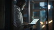 © Gorodenkoff - Handsome Black African American Male is Standing in Meeting Room Behind Glass Walls with Laptop Computer in an Creative Agency. Project Manager Wearing White Jumper and Working on App User Interface.