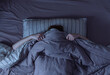 © 22Imagesstudio - Top view of scared woman in bed covering her face with blanket.