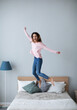 © BestForYou - Cute happy young woman jumping on the bed at home.
