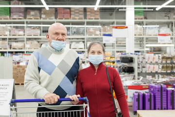 Wall Mural - Elderly couple shopping in a supermarket and wearing medical face masks