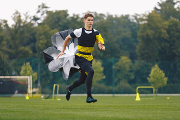 Wall Mural - Youth Football Player Running with Parachute. Soccer Football Endurance Training. Speed or Sprint Testing. Professional Soccer Strength Test. Young Boy in Football Club Exercising on Training Venue