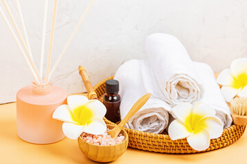 Canvas Print - Spa massage Aromatherapy body care background. Spa herbal balls, cosmetics, towel and tropical flowers on orange table. Top view, flat lay, overhead, copy space. Beauty and health care concept