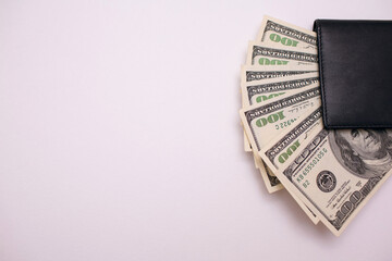 Cash from one hundred dollar bills in a wallet on a white background top view