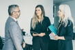 © Mangostar - Positive confident business partners meeting and discussing collaboration, holding folder and tablets. Side view. Communication or partnership concept
