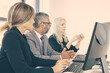 © Mangostar - Company managers meeting. Team of professionals sitting at workplace with monitors together and discussing project. Side view. Business meeting concept