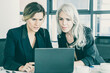 © Mangostar - Focused business ladies looking at laptop display while sitting at table with cups of coffee in office. Teamwork and communication concept