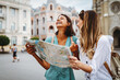 canvas print picture - Fun, friends, travel and tourism concept. Beautiful girls looking for direction in the city