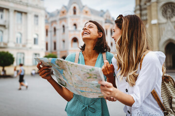 fun, friends, travel and tourism concept. beautiful girls looking for direction in the city
