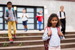 © JackF - Cute curly tween girl with backpack walking with other schoolchildren to school campus after lessons on warm fall day.