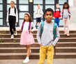 © JackF - Portrait of African american tweenager walking outside school building on autumn day, going to lessons.