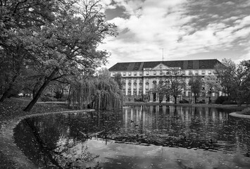 Poster - Trees and a pond in the park and a historic building during autumn