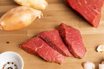 A set of beef meat, onion shallots and spices laid out on the table.