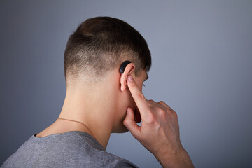 A young man is wearing a hearing aid. ENT equipment concept 