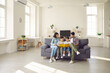 © Studio Romantic - Happy people sitting together on sofa in modern interior of new house or studio apartment. Family with kids reading book on comfy gray couch in the living-room and enjoying quiet leisure time at home