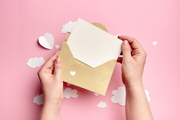 Greeting card mockup in female hands with paper decorations on pink background