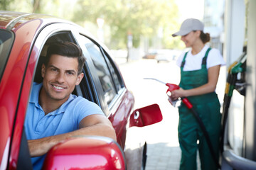 Canvas Print - Man sitting in car while young worker refueling his auto at modern gas station