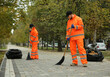 Street cleaners sweeping fallen leaves outdoors on autumn day