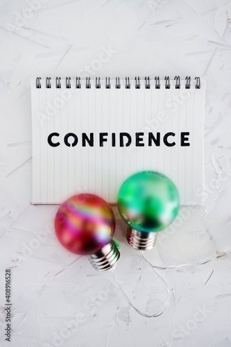 confidence text on notepad surrounded by colorful light bulbs symbol of ideas, positive attitiude and psychology