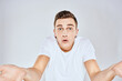 © SHOTPRIME STUDIO - Nice man in a white t-shirt gestures with his hands emotions surprise studio