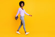 Full body profile photo of pretty dark skin person walking arm hold laptop isolated on yellow color background