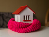 Fototapeta  - house in winter - heating system concept and cold snowy weather with model of a house wearing a knitted cap