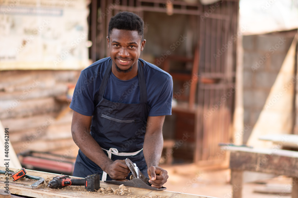 young african carpenter smiling while working - obrazy, fototapety, plakaty 