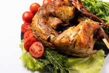 Rabbit Meat Baked With Vegetables And Herbs On A Plate On A Black White Background. With Tomatoes And Lettuce