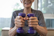 © Satjawat - Close Up,hands of senior people holding dumbbells while working out,old elderly lifting dumbbell weights,daily workouts at home,exercise regularly,health care,healthy lifestyle and strong concept