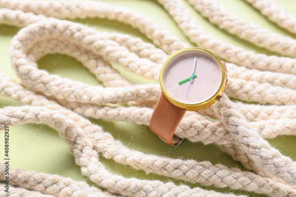 Stylish wrist watch with rope on color background