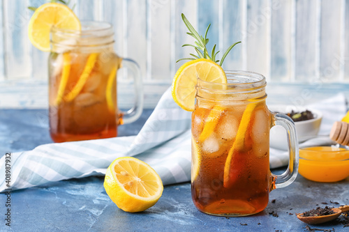 Mason jars of cold black tea with lemon on color background © Pixel-Shot