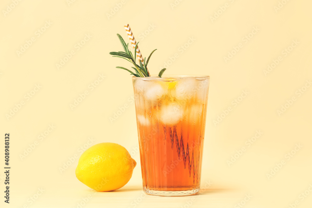 Glass of cold black tea with lemon on color background