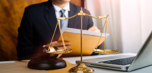 Justice and law concept.Male judge in a courtroom with the gavel, working with, computer and docking keyboard, eyeglasses, on table in morning light