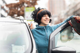 Fototapeta Na drzwi - Junge Frau aussen mit Elektroauto, carsharingauto