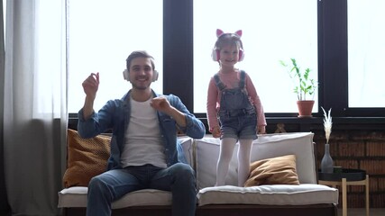 Wall Mural - Charming girl and her handsome young dad in headphones are listening to music