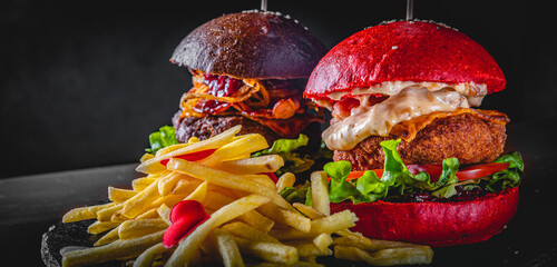 Wall Mural - two burger with meat, cheese, vegetables and french fries on dark black background