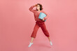 © Look! - Full length view of brunette woman holding blue valise. Studio shot of caucasian lady with suitcase posing on pink background.