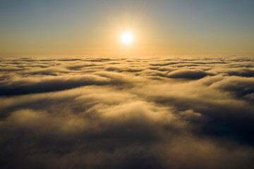 Wall Mural - striking aerial view of the sunset sky with the clouds below us. the shadows projected from the sun 