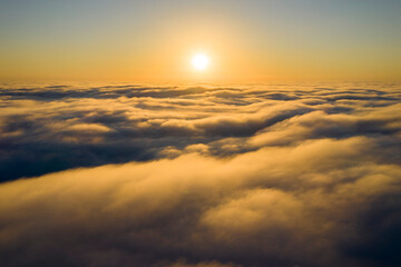 Wall Mural - striking aerial view of the sunset sky with the clouds below us. the shadows projected from the sun 